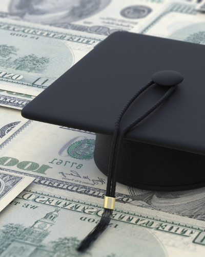 Graduation cap sitting on money.